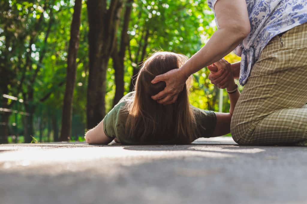 Old woman helping a fainted girl to get back on her feet