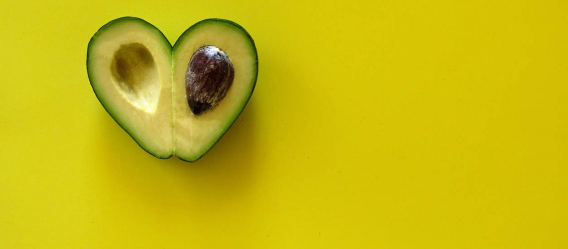 Heart-shaped slices of avocado on yellow background