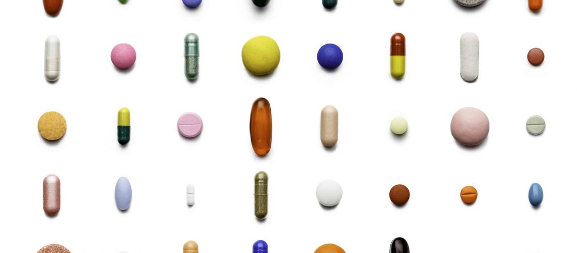 Array of large group of assorted capsules and pills on white background. High resolution image.