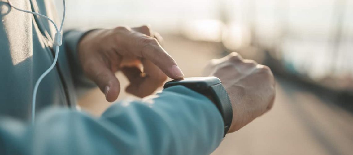 sport man checking at smartwatch during training and running in the park.